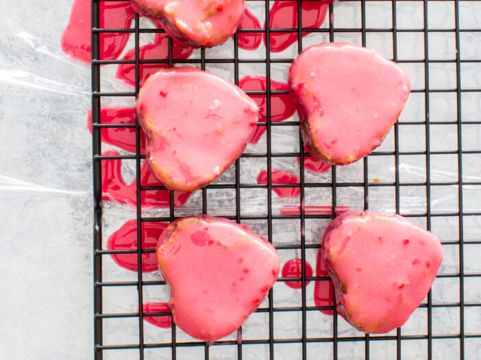 Conversation Heart Pops laying on wire drying rack after being covered in icing