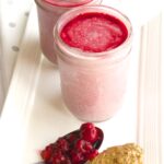 Almond Butter & Raspberry Breakfast Smoothies in mason jars with one spoon of raspberries and one spoon of almond butter