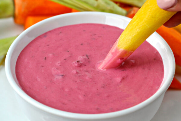 Razzy Ranch Dressing with someone dipping yellow carrot, served with multi colored carrots