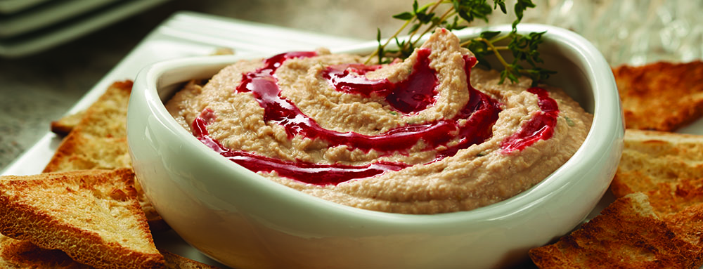 Bowl of raspberry hummus garnished with thyme