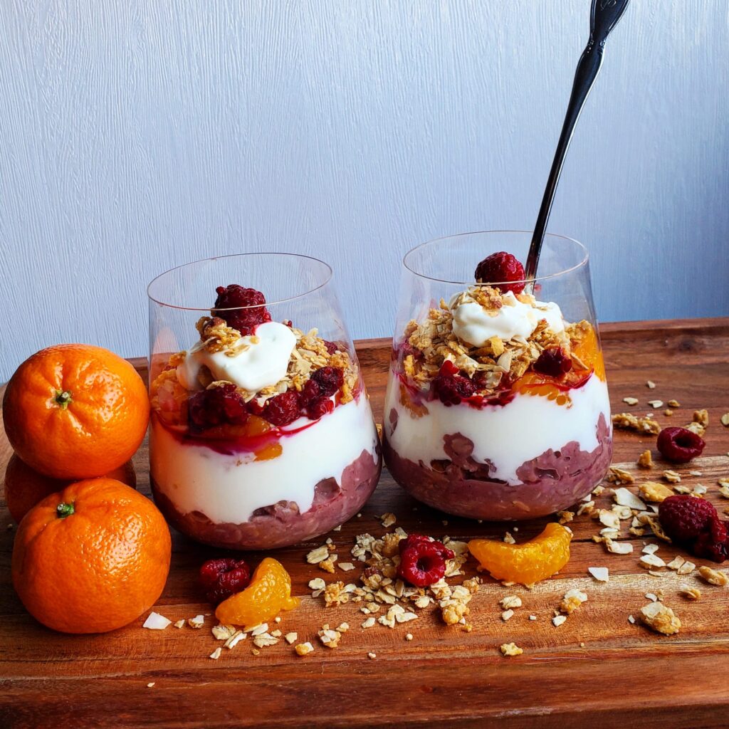 Raspberry Creamsicle Parfait layered in stemless wine glass with orange slices and granola