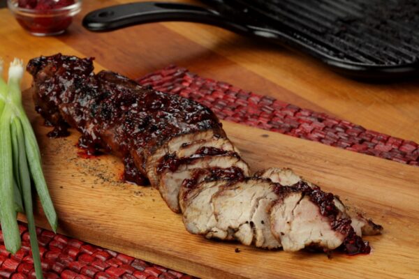 Grilled Pork With Balsamic-Red Raspberry Reduction, sliced on wood platter