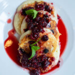 Three pancakes topped with Raspberry Cane Syrup and mint
