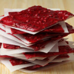 Red Raspberry Fruit Leather stacked with parchment paper in between each piece