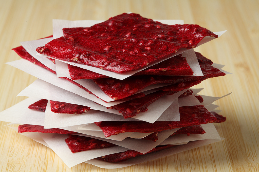Red Raspberry Fruit Leather stacked with parchment paper in between each piece