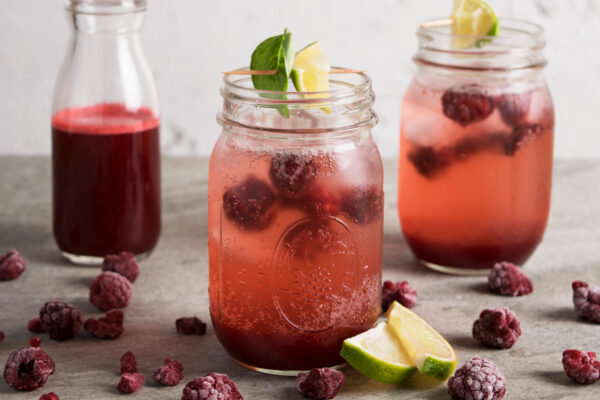 Frozen Raspberry Shrub served in mason jars garnished with lime