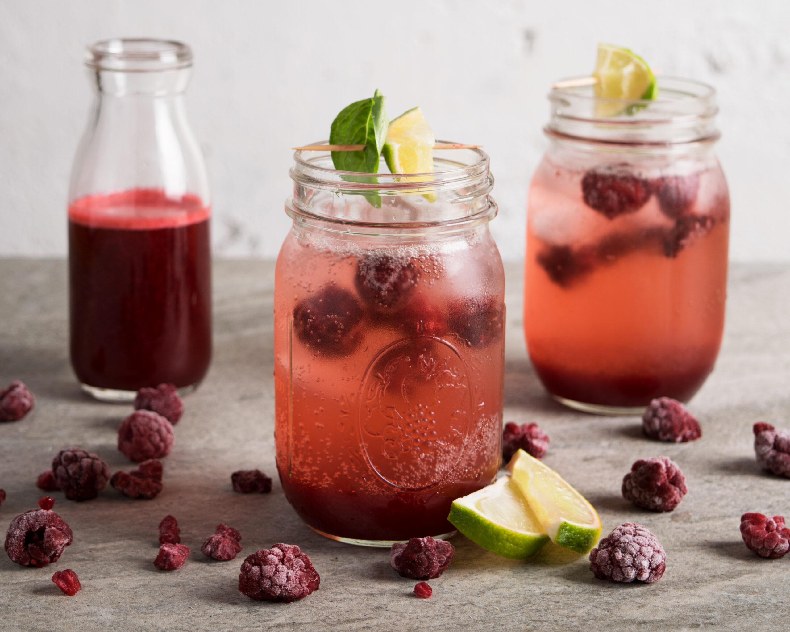 Frozen Raspberry Shrub served in mason jars garnished with lime
